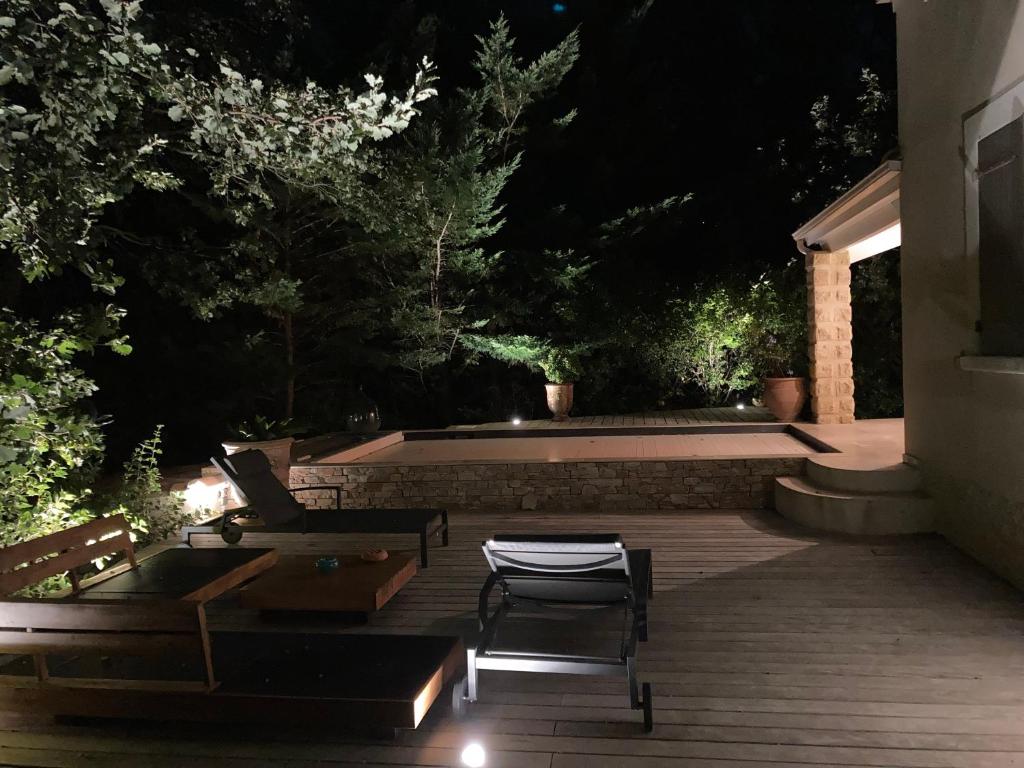 a backyard at night with a pool and chairs at La Balouvière Villa entre Cévennes et Provence in Laudun