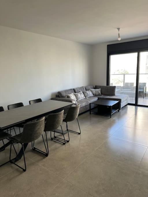 - un salon avec un canapé, des tables et des chaises dans l'établissement Appartement Guivat Olga 4 pièces proche mer, à Hadera