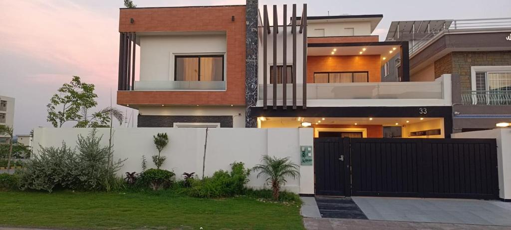 una casa con una puerta negra y una valla en Haven Lodge - charming home with Hot tub, Garden, Mountain view, en Islamabad