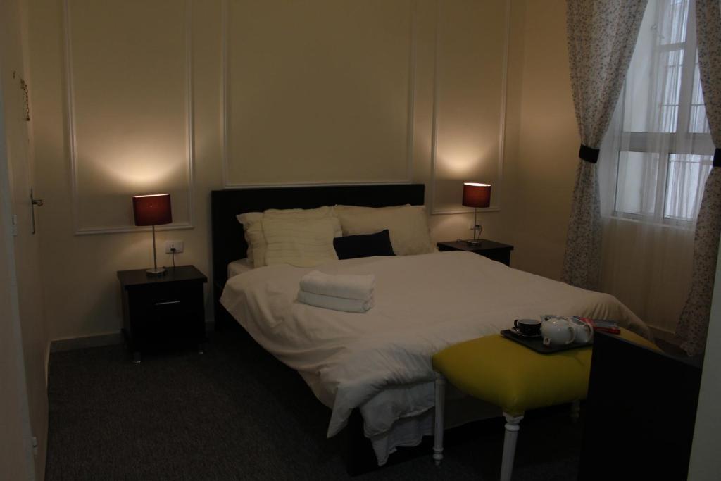 The 1st Night Hotel في عمّان: غرفة نوم بسرير مع مصباحين وكرسي اصفر