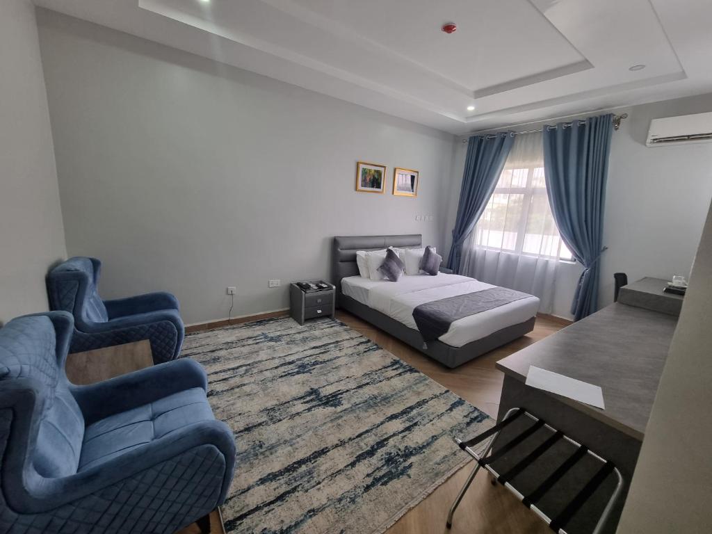 una camera con un letto e due sedie e un tavolo di Solace Suites and Homes Maiduguri a Maiduguri