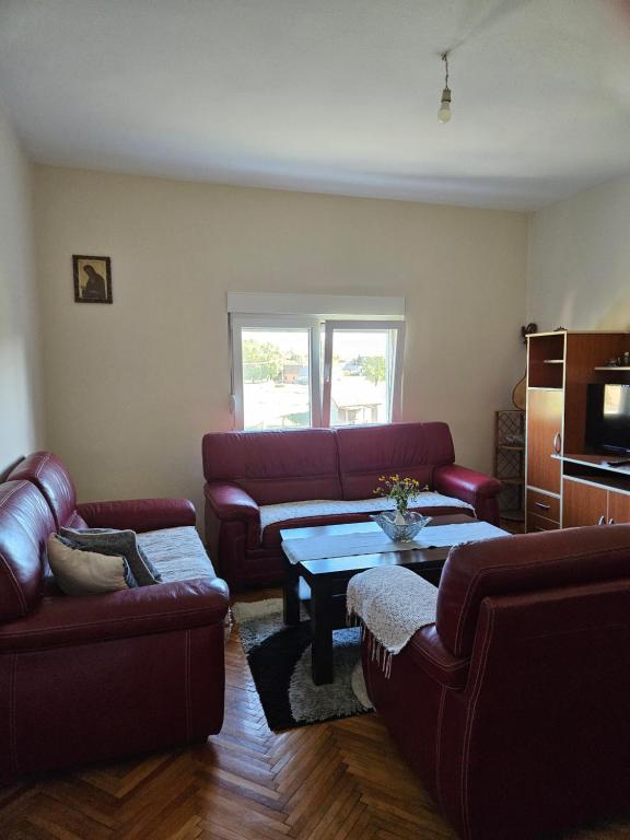 Sala de estar con sofás rojos y mesa de centro en Apartman Gajic, en Nikšić