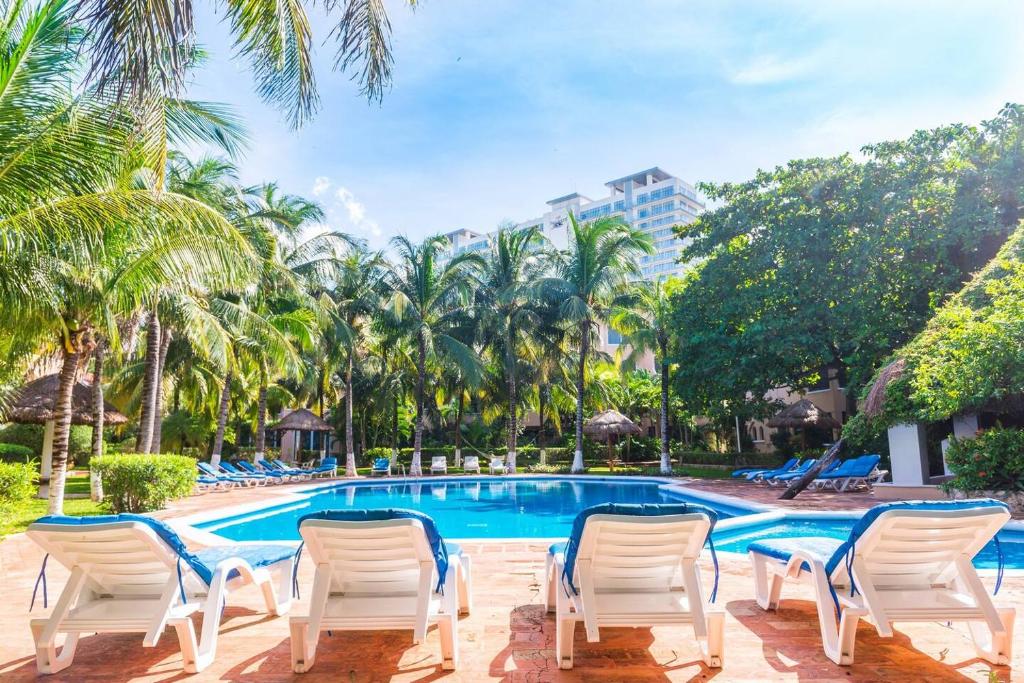 a swimming pool with white chairs and palm trees at Marmaris Apartment in Cancún