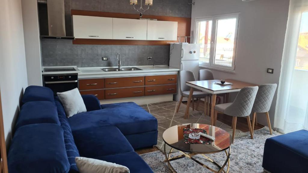 Il comprend un salon avec un canapé bleu et une cuisine. dans l'établissement Flavio Apartament Comfort, à Pogradec