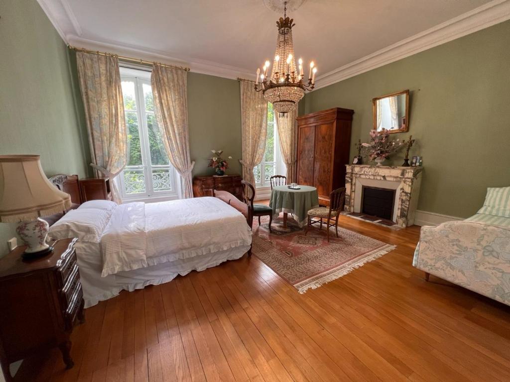 a bedroom with two beds and a fireplace and a chandelier at LES PAYRATONS in Saint-Gérand-le-Puy