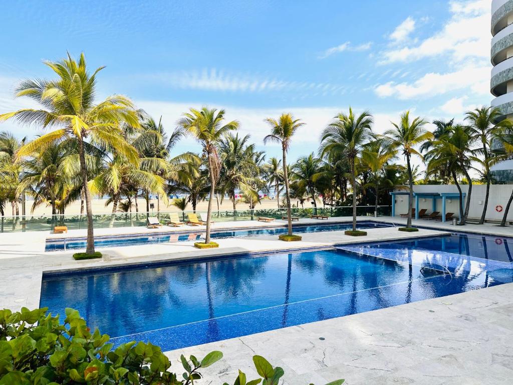 a large swimming pool with palm trees in a resort at Apartamento Delux Morros-Tolusa in Cartagena de Indias