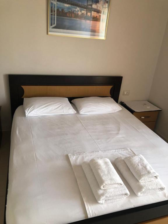 a bed with white sheets and two white towels at Vila Alicani in Fier