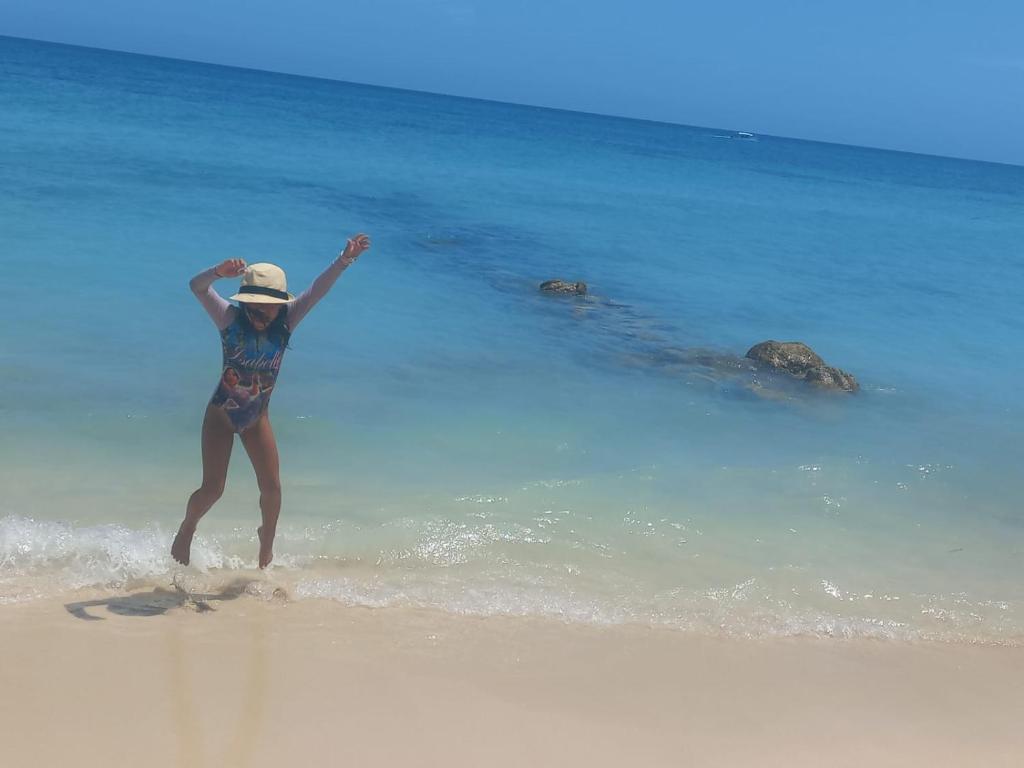 a woman standing on a beach with her arms in the air at Cabañas Palos Locos in Baru