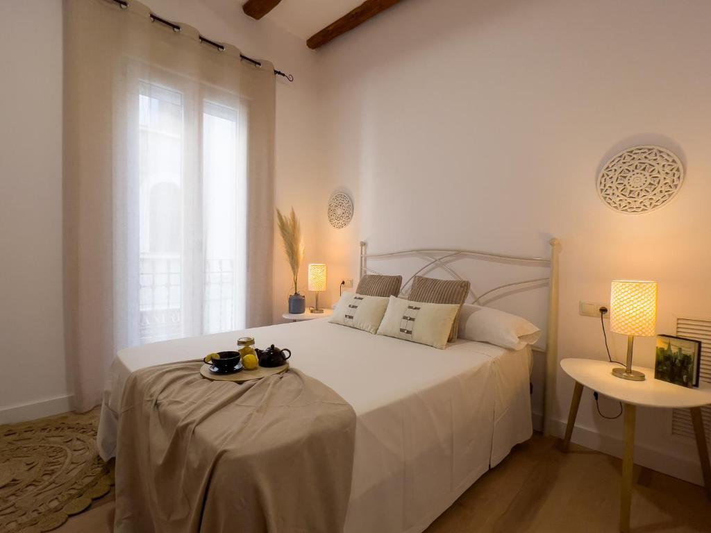 a bedroom with a large white bed with a window at Somos Genius! Siéntete como en casa, en el corazón de Tarragona in Tarragona