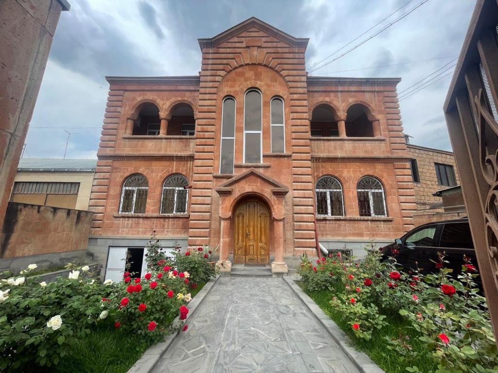 a brick church with a wooden door and flowers at Najaryan's Family Guest House in Vagharshapat