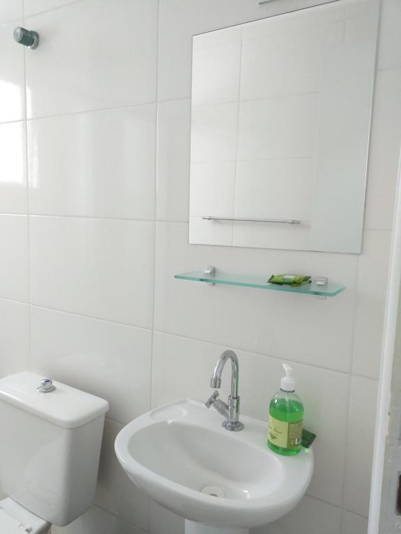a white bathroom with a sink and a toilet at Apartamento Vista Mar Mongaguá in Mongaguá