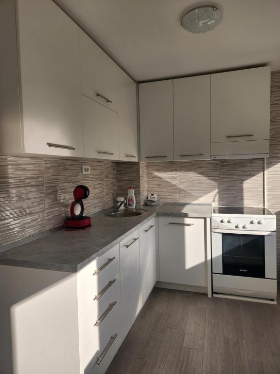 een witte keuken met witte kasten en een fornuis bij Stan na dan Nova Varoš in Banja Luka