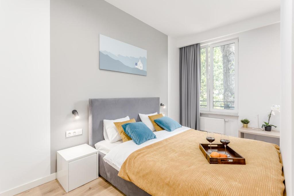 a white bedroom with a large bed with blue pillows at Warsaw City Apartments EXPO in Warsaw