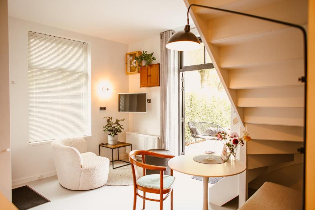 a living room with a table and chairs and a staircase at Boutiquehotel & Tiny houses PLEK17 in Milsbeek