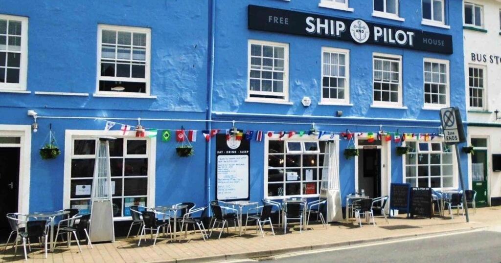 un edificio azul con mesas y sillas delante de él en The Ship and Pilot Inn, en Ilfracombe