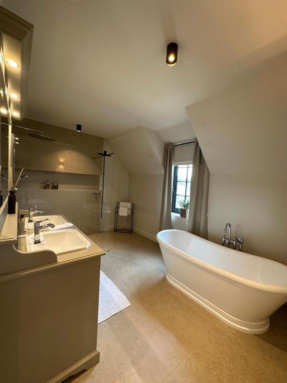 a large bathroom with a large tub and a sink at Het Herenhuis in Genk