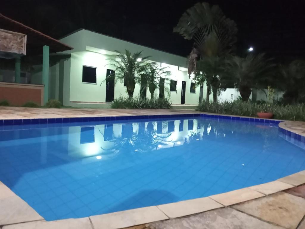 una piscina por la noche con una casa en el fondo en Pousada das Acácias, en Carananduba