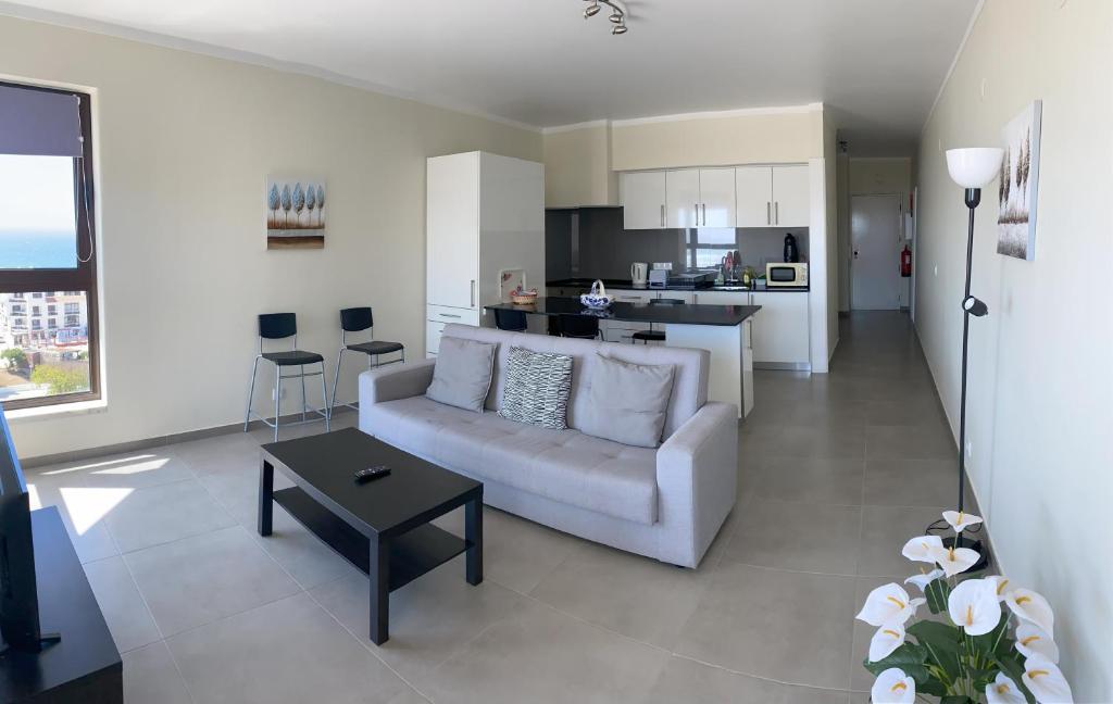 sala de estar con sofá blanco y cocina en Appartement avec vue imprenable sur l'océan, en Praia da Areia Branca