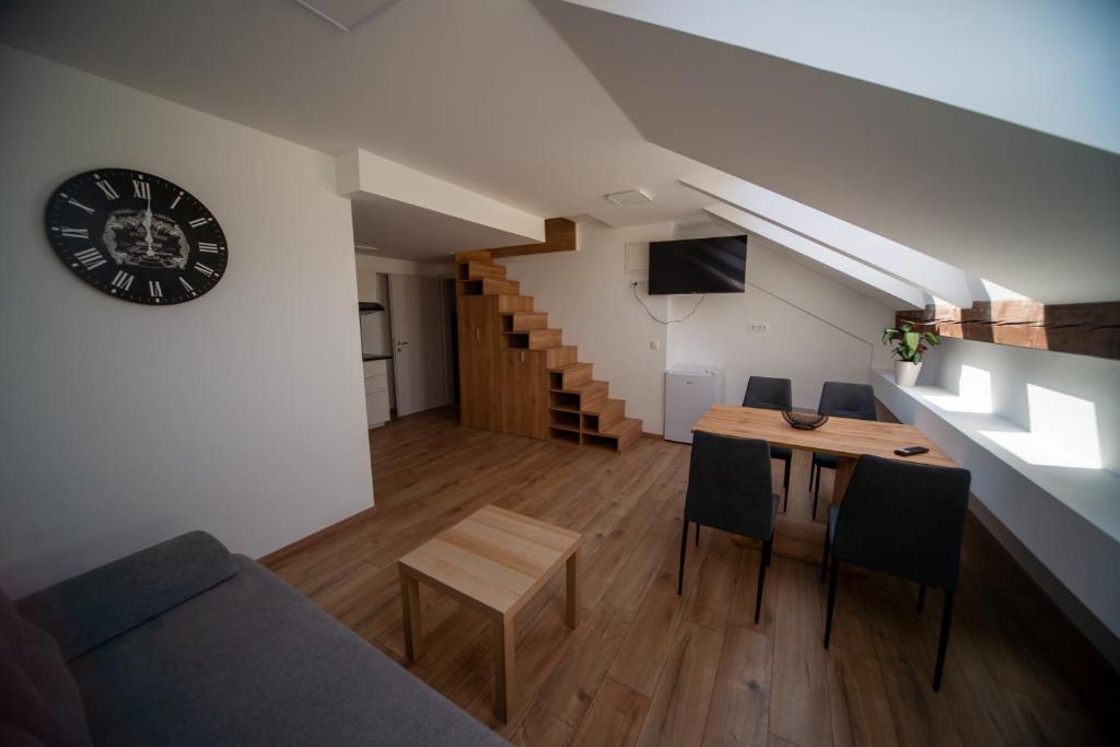 a living room with a couch and a table and a clock at Sport apartments in Radovljica