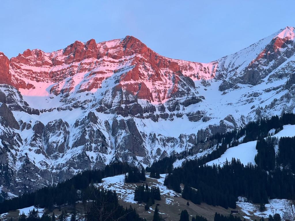 a mountain covered in snow and red rocks at Schönes 2-Zimmer Studio mit grossem Balkon und Bergpanorama - 400m von Talstation Sillerenbahn in Adelboden