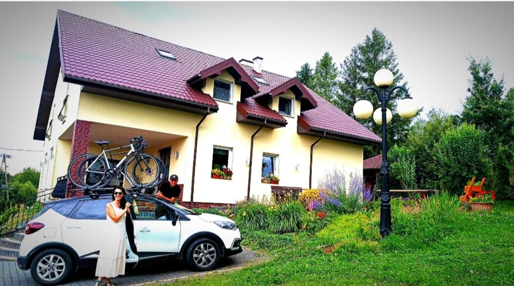 a woman standing next to a car with a bike on the roof at Frankowo in Teodorówka