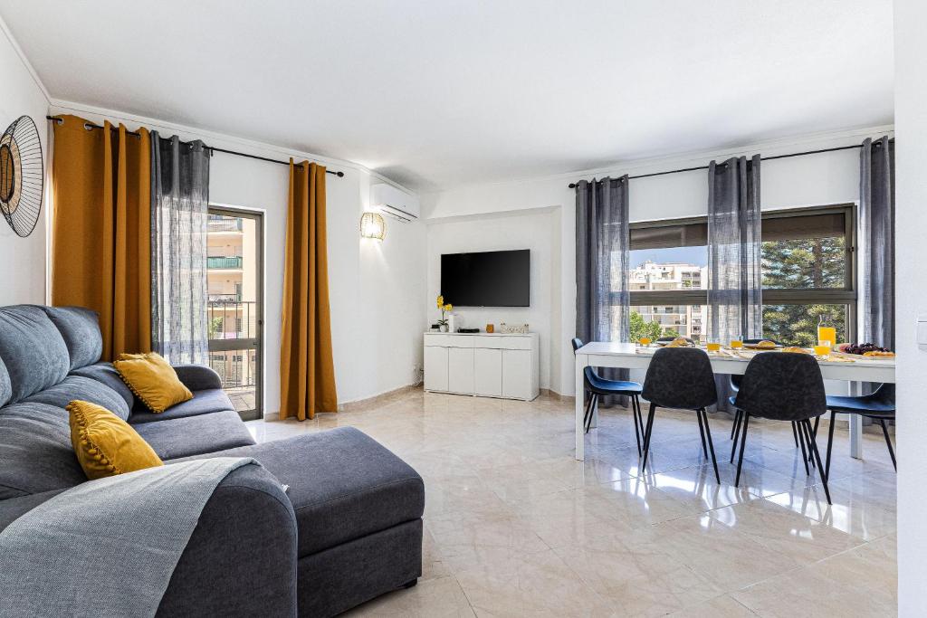 a living room with a couch and a table with chairs at Beachside Bliss in Armação de Pêra