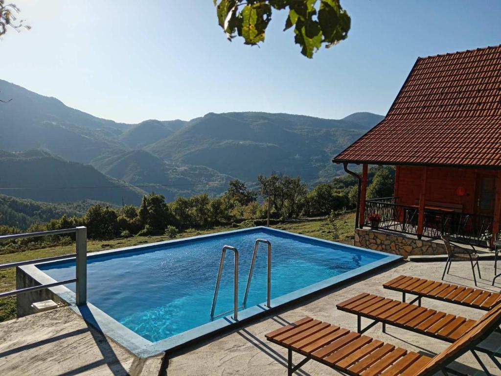 uma piscina com duas cadeiras e uma casa em Dobar pogled em Bajina Bašta