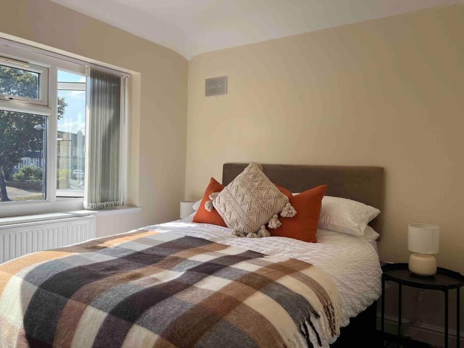 ein Schlafzimmer mit einem Bett mit orangefarbenen Kissen und einem Fenster in der Unterkunft Large House/Contractors/Families in Birmingham