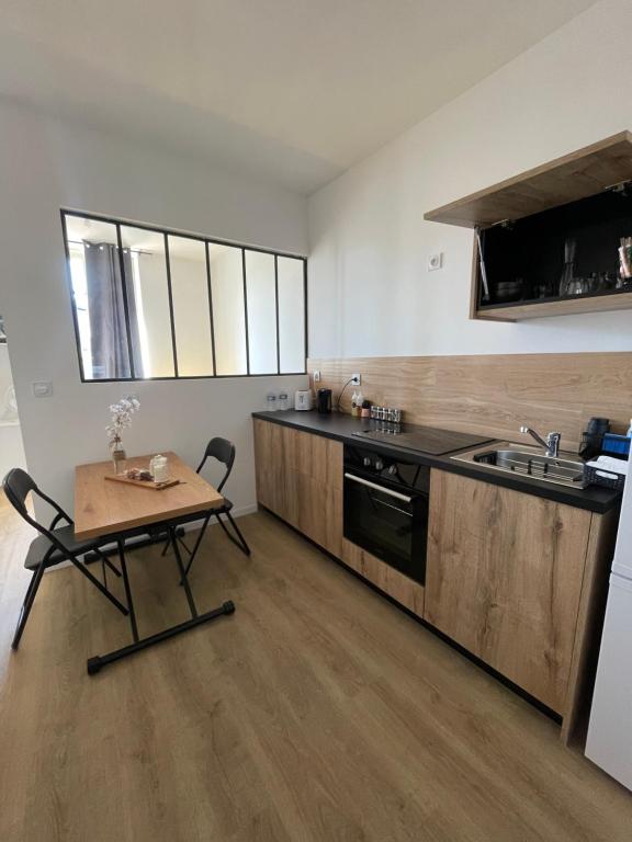 eine Küche mit einem Holztisch, einem Tisch und einem Waschbecken in der Unterkunft Studio Design - Terrasse - Proche du stade in Saint-Étienne