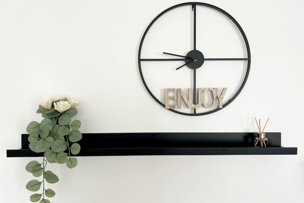 un reloj negro en una pared blanca con una planta en Maison avec jardin proche de Paris, en Mormant