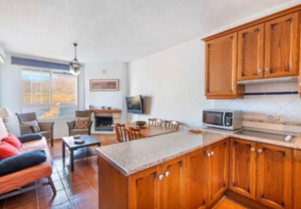 a kitchen with wooden cabinets and a living room at Apartamento en las salinas de Cabo de Gata in El Pozo del Cabo