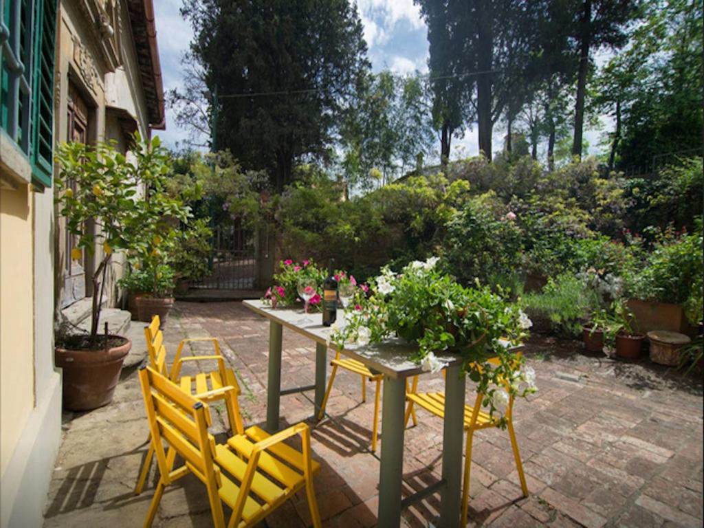 a table with yellow chairs and plants on a patio at B&B Borgo Ponte dell'Asse in Florence