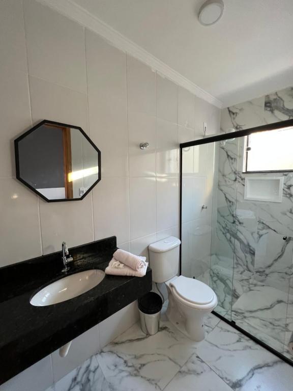 a bathroom with a sink and a toilet and a mirror at Colliseu Hotel Pousada in Aparecida