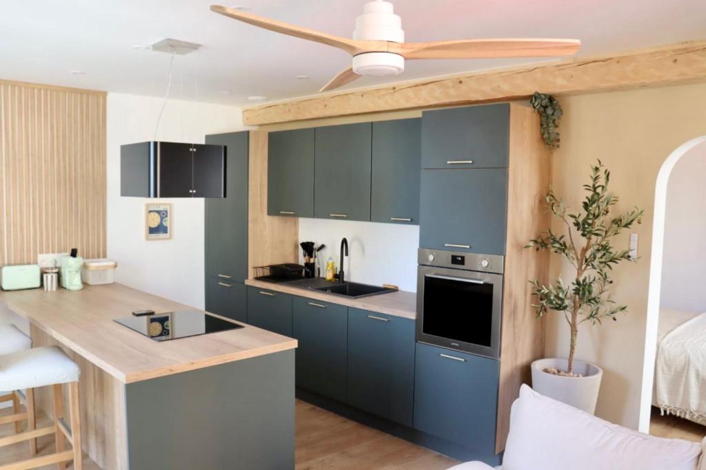 een keuken met blauwe kasten en een plafondventilator bij Au cœur de Hyeres, Idéal pour les couples ! in Hyères