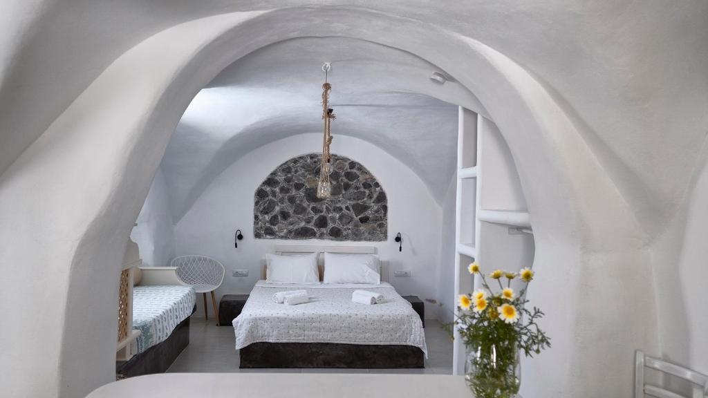 een slaapkamer met een bed in een witte kamer bij Mythos Traditional Stonehouse in Kamari
