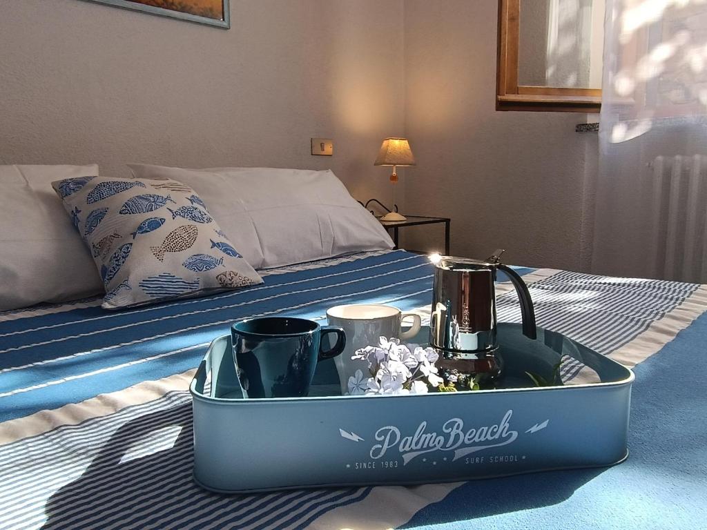 un vassoio con due tazze e un bollitore per il tè su un letto di Appartamento nel parco a Marciana