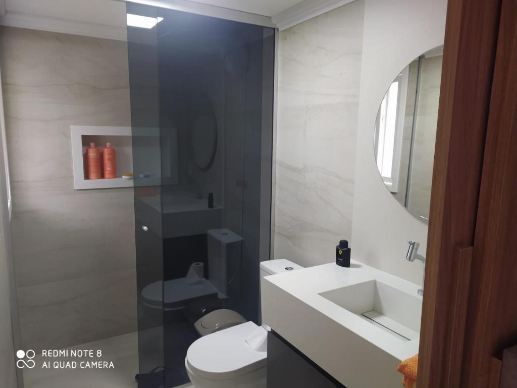 a bathroom with a toilet and a sink and a mirror at Suíte aconchegante in Santa Cruz do Sul