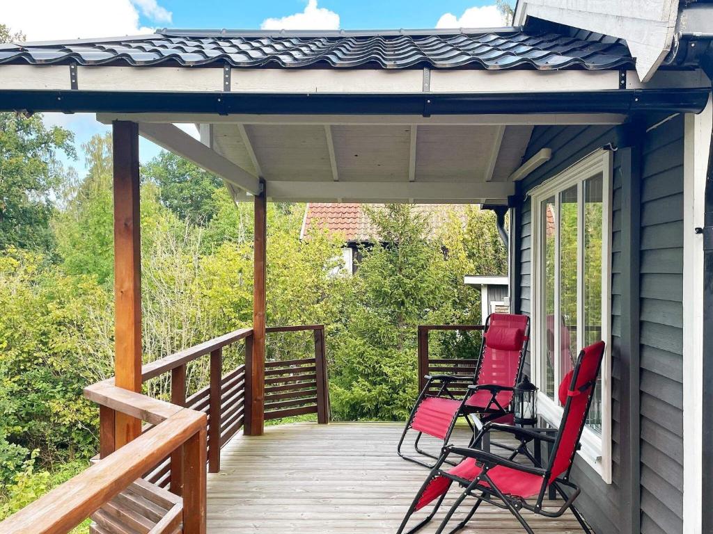 Dos sillas rojas en el porche de una casa en 6 person holiday home in GR NNA, en Gränna
