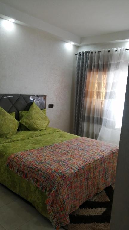 a bedroom with a bed with green sheets and a window at Appartement de luxe in Dakhla