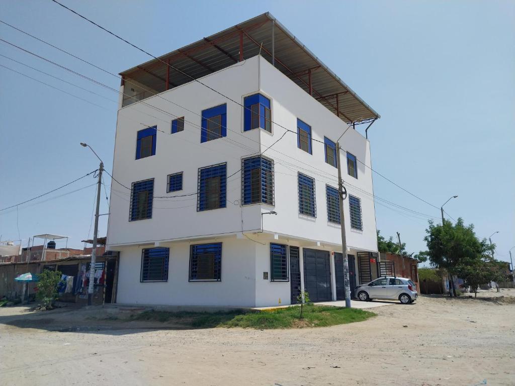 ein weißes Gebäude mit blauen Fensterläden und einem Auto in der Unterkunft Luz de Luna in Piura