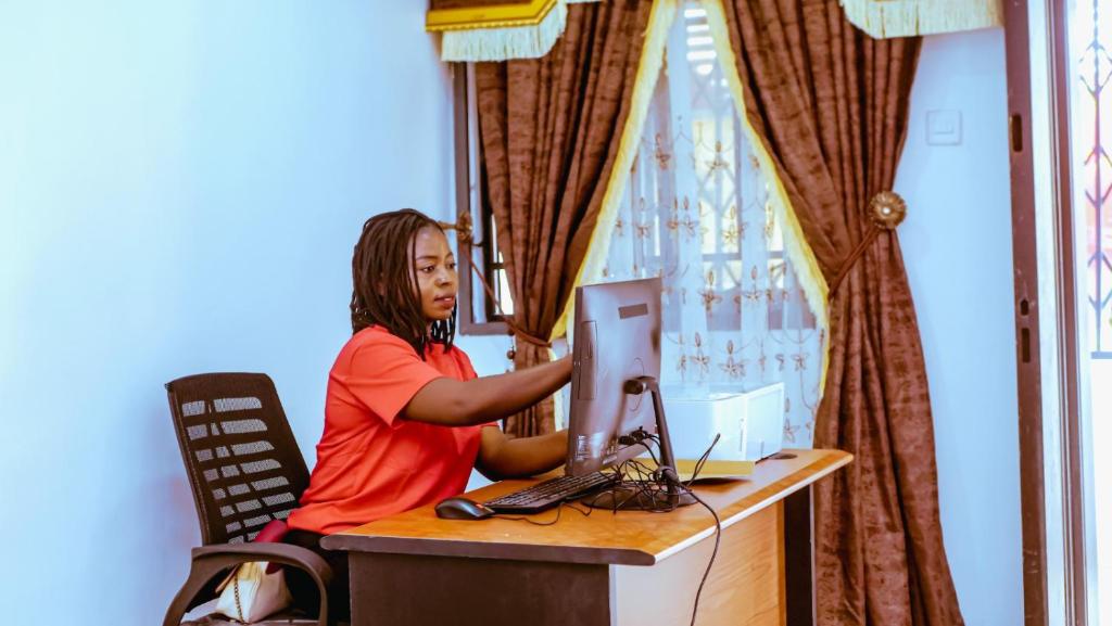 uma mulher sentada numa secretária com um computador em Select Captivating Room with 1kingsized bed em Abuja