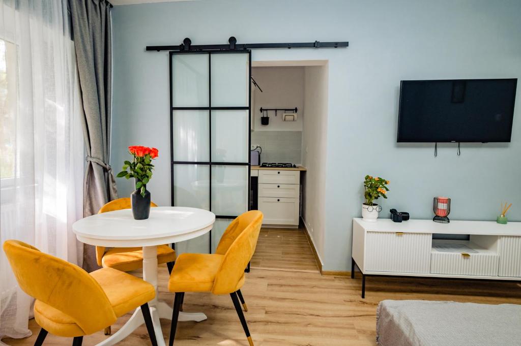 uma sala de estar com uma mesa e cadeiras amarelas em Modern studio D-va N em Zalău