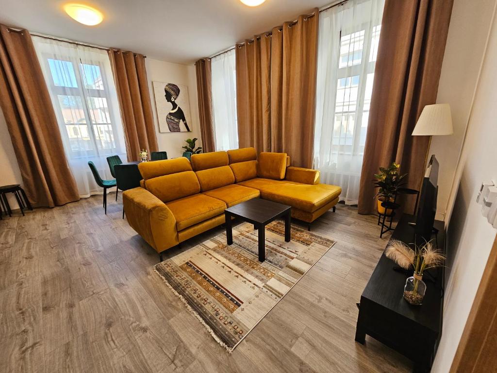 - un salon avec un canapé jaune et quelques fenêtres dans l'établissement Velký byt 3+kk Klicperova, 2 ložnice, à Hradec Králové