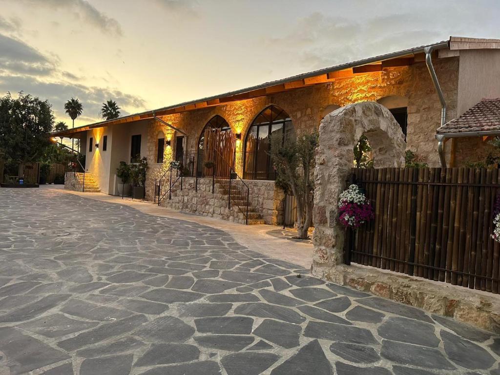 a house with a stone driveway in front of a building at Hagafen Boutique Suites in Zikhron Ya‘aqov