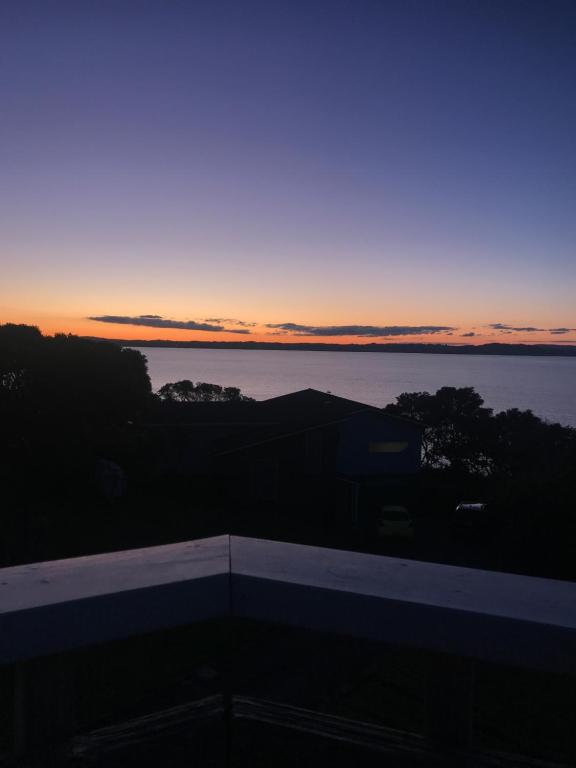 einen Balkon mit Blick auf das Meer und den Sonnenuntergang in der Unterkunft Sea View Apartment in Whangaparaoa