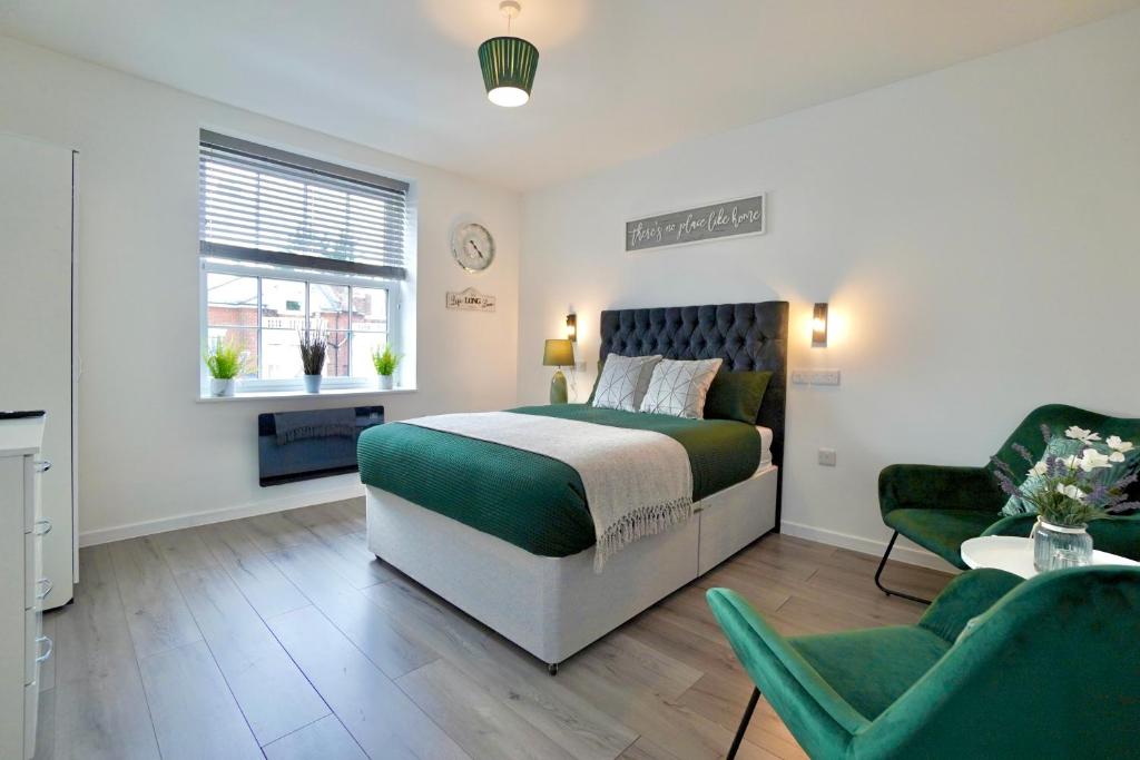 a bedroom with a bed and two green chairs at Luxury Flats in Southsea Portsmouth in Portsmouth