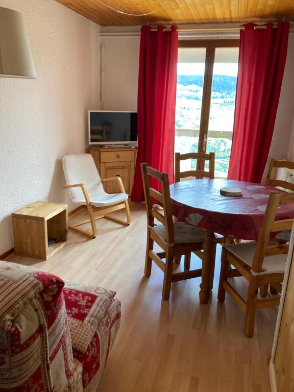 uma sala de estar com uma mesa e cadeiras e uma janela em Les Pâturages em La Bresse