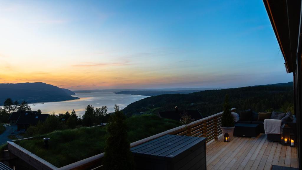 une femme debout sur une terrasse avec vue sur un lac dans l'établissement Hide Hut - Amazing view 50 min from Oslo, à Stange