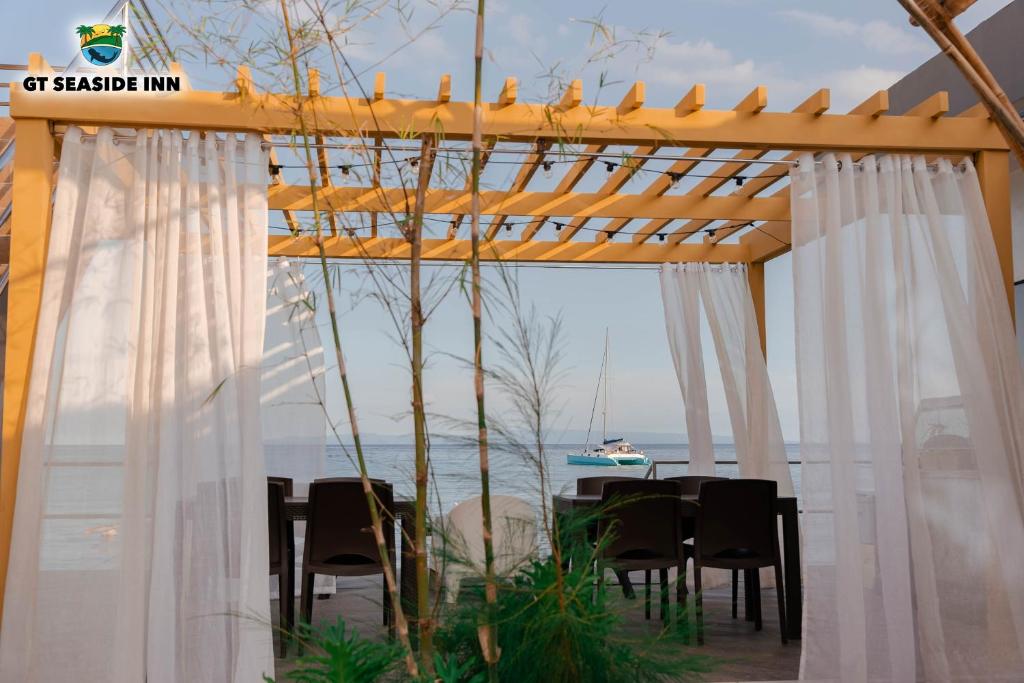 オスロブにあるGT シーサイド インのパーゴラの下にテーブルと椅子、海の景色を望む