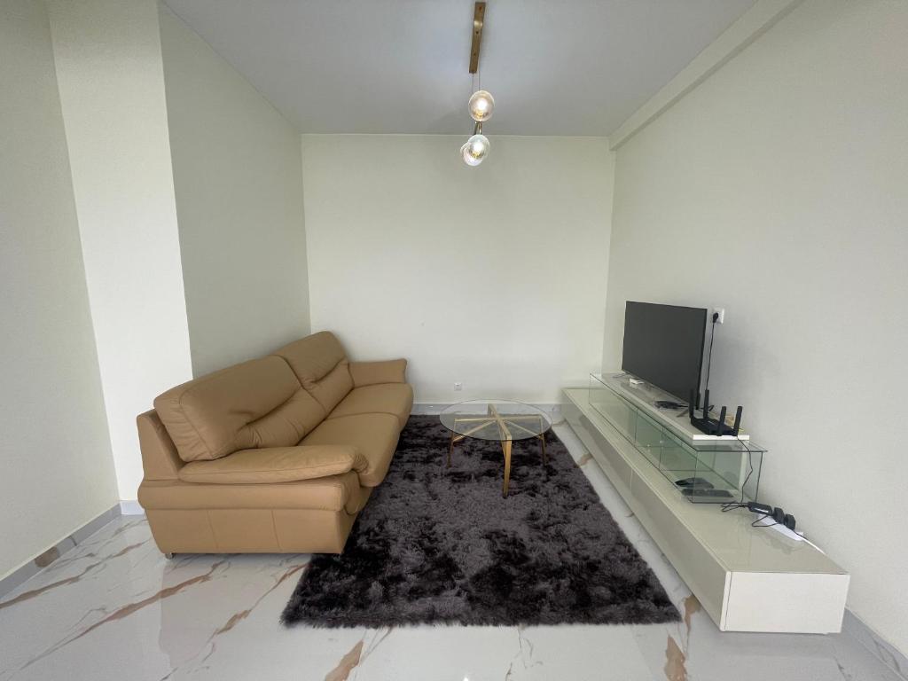 ein Wohnzimmer mit einem Sofa und einem TV in der Unterkunft Pimenova Residence in Luanda